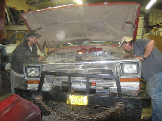 1979 Ford F-150 front view, red, with open hood, winch on bumper, two men working on engine