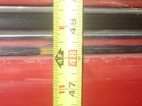 1979 Ford F-150 - Measuring tape is placed against a red surface with black trim details.