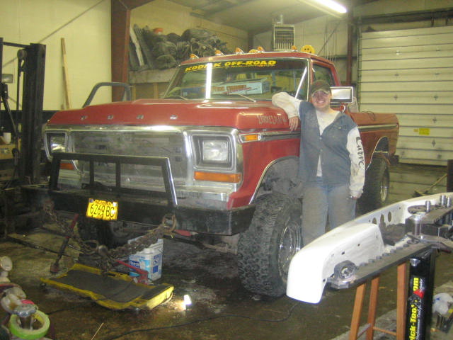 Red 1979 Ford F-150 pickup truck with a large front bumper and a person standing beside it