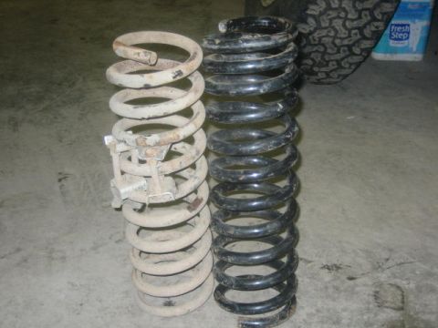 1979 Ford F-150 - Comparison of two suspension springs, one showing signs of rust and wear, next to a newer black spring. A tire and a container of cat litte…