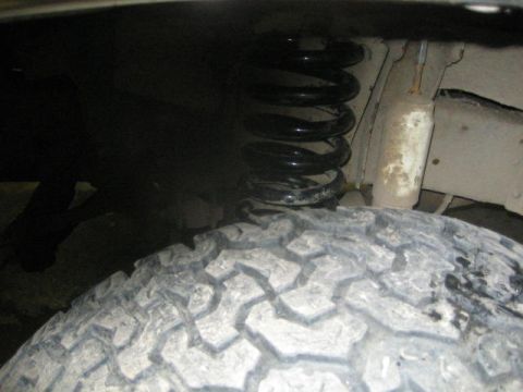 1979 Ford F-150 - A view of the suspension system, including a coil spring and shock absorber, positioned next to a tire.