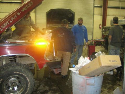 1979 Ford F-150 - Mechanics work on a red 1979 Ford F-150 in a garage, with another vehicle in the background.