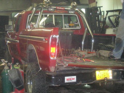 1979 Ford F-150 - A red 1979 Ford F-150 pickup truck is shown from the rear, with its bed filled with suspension springs and tools.