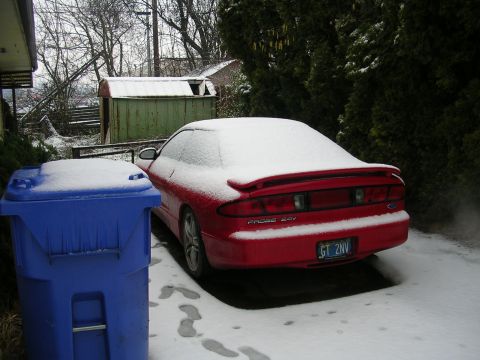 1996 Ford Probe - A red Ford Probe sits covered in snow next to a blue trash can on a winter day.