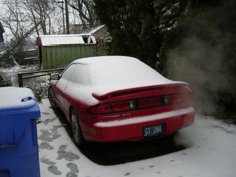 1996 Ford Probe - A red 1996 Ford Probe sits covered in snow, with exhaust visible.