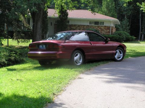 1993 Ford Probe - A 1993 Ford Probe is parked on the lawn next to a paved driveway, with a house visible behind it.
