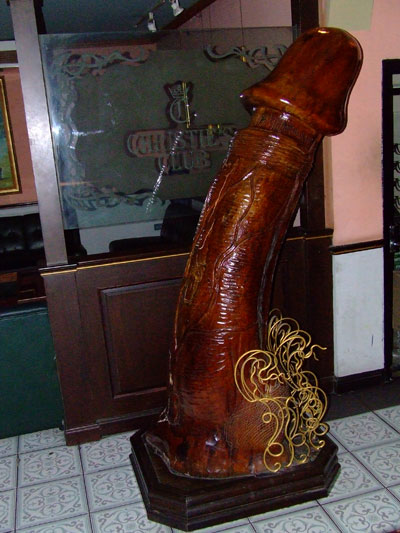 1966 Ford Bronco - A large, carved wooden sculpture resembling a phallus, adorned with gold wire, stands prominently indoors.