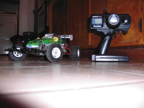 1993 Ford Bronco - A green remote control car sits on a tiled floor next to its controller.