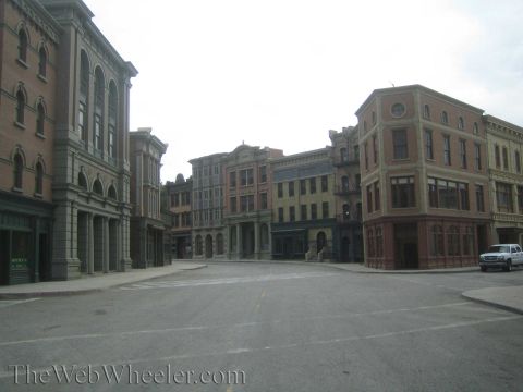 1990 Ford Bronco - empty studio backlot street flanked by multi-story facades built to resemble an old downtown, with a white truck parked at right.