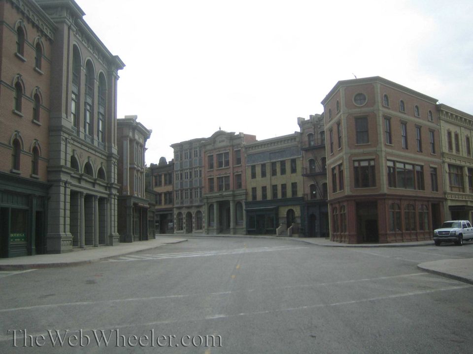 Empty city-street movie backlot lined with multi-story brick and stone building facades