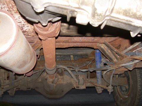1988 Ford Bronco - The undercarriage of a heavily rusted vehicle reveals its drivetrain and suspension parts.
