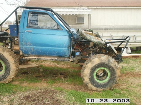 1992 Ford Mustang - Customized blue off-road vehicle with a prominent roll cage and oversized tires, photographed outdoors.