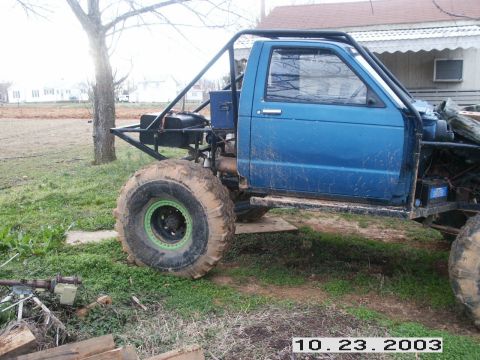 1992 Ford Mustang - Custom off-road truck with a roll cage and oversized tires is shown outdoors.