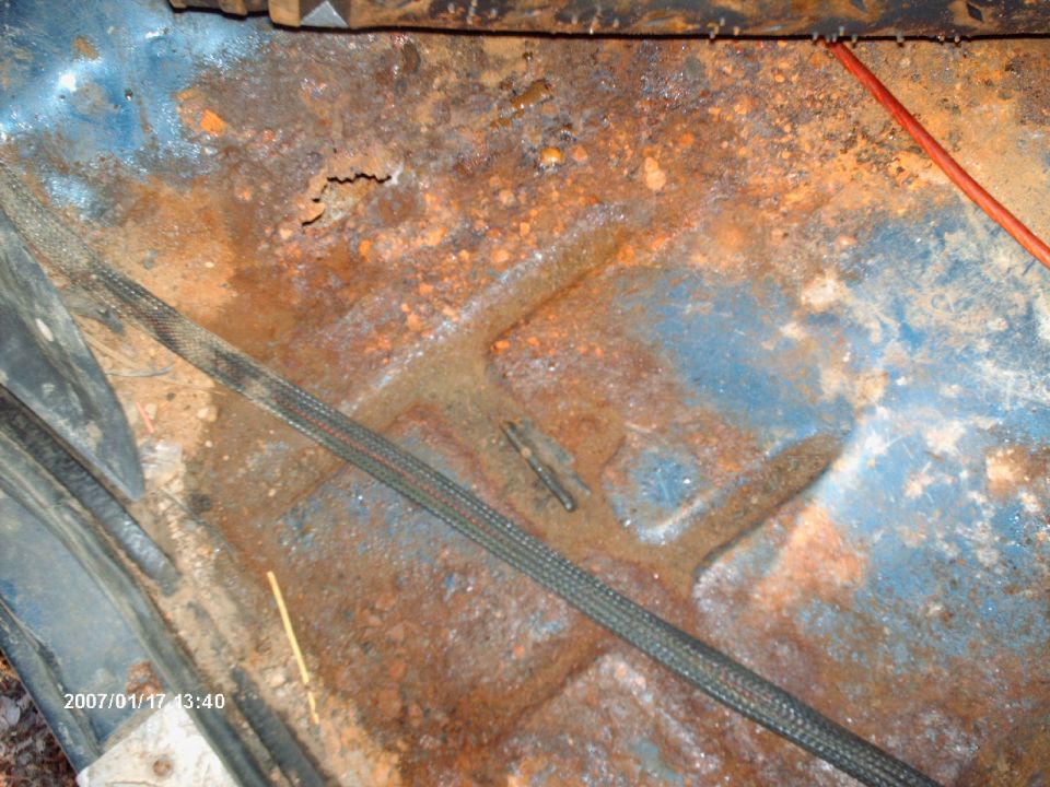 rusted out blue floor pan with some wiring