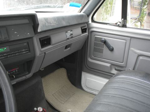 1999 Ford F-800 - The interior of a truck shows the dashboard, door panel, and passenger seat, with a radio and floor mat visible.