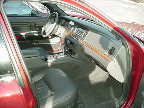 2002 Ford Crown Victoria - The interior of a red vehicle is shown, leather seats and a wood-grain trim on the dashboard.