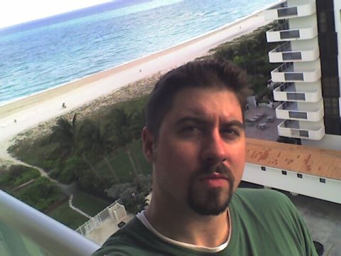 1984 BMW 3 Series - Self-portrait on a balcony with a view of the ocean and a modern hotel building.