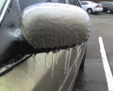 2000 Ford Crown Victoria - A car's side mirror and door are encased in ice, with icicles dripping from the bottom edge.