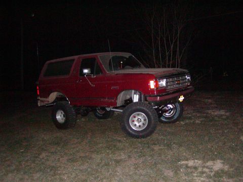 1991 Ford Bronco - This lifted 1991 Ford Bronco sits on a grassy area at night, its red paint reflecting the available light.