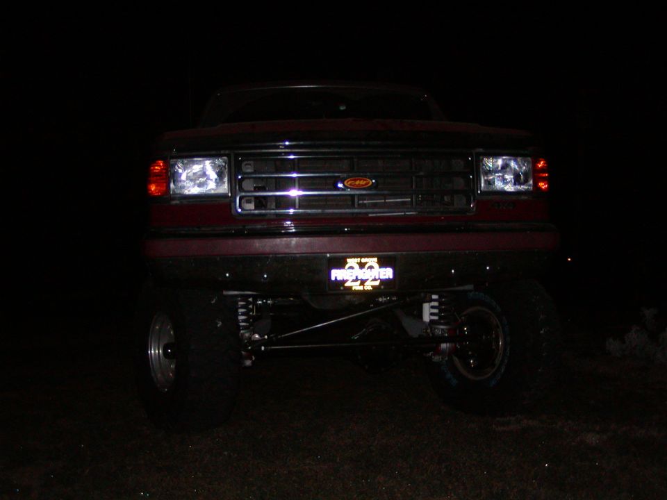 1991 Ford Bronco front view at night, showing grille, headlights, and custom license plate