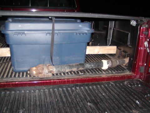 1991 Ford Bronco - A driveshaft and a blue toolbox are secured in the bed of a red pickup truck.