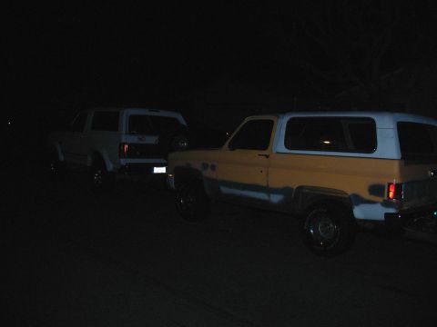 1993 Ford Bronco - Two SUVs are parked side-by-side in the dark, with one vehicle's rear facing the camera.