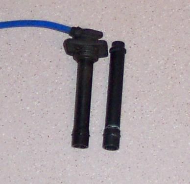 1994 Ford Probe - Close-up of two spark plug wire boots, one connected to a blue wire, against a speckled background.