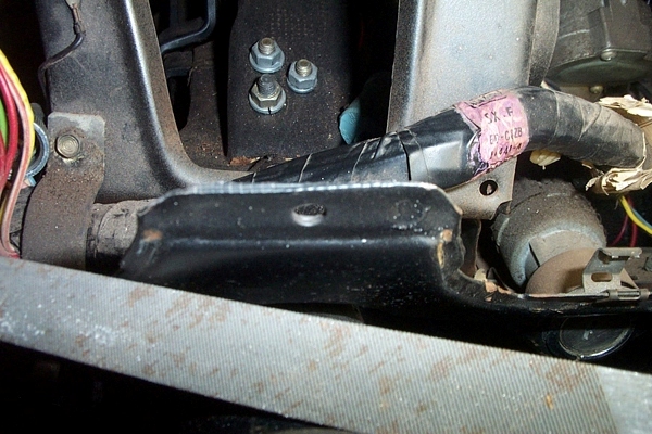 Under-dash close-up of steering column bracket and taped wiring harness