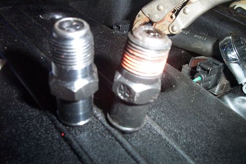 1999 Chrysler 300M - Close-up of two threaded metal parts, one of which is glowing orange, with pliers gripping it.