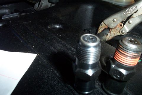 1999 Chrysler 300M - Close-up of engine parts and pliers working on a hose.