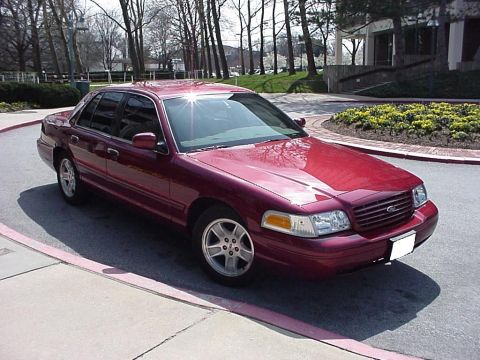 2002 Ford Crown Victoria - This red 2002 Ford Crown Victoria sedan is parked curbside on a sunny day.