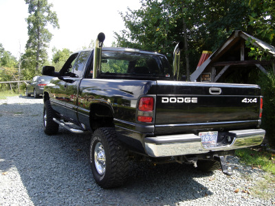 2002 Dodge 2500 - This black Dodge 2500 pickup truck features chrome exhaust stacks and a 4x4 decal on the tailgate.