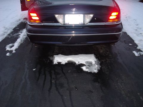 2000 Ford Crown Victoria - Rear view of a 2000 Ford Crown Victoria parked on a wet driveway with snow patches.