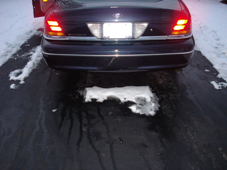 Rear view of a dark blue Ford Crown Victoria LX with lit tail lights and dual chrome exhaust tips
