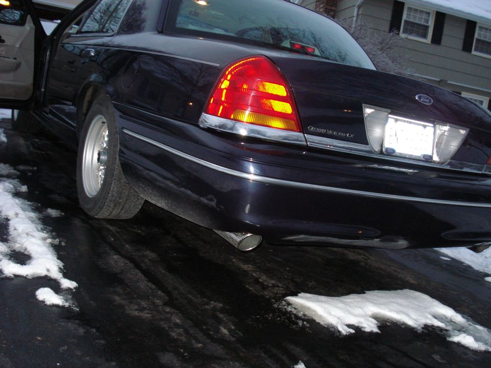 Low rear view of dark blue Ford Crown Victoria LX with chrome exhaust tip on snowy drive