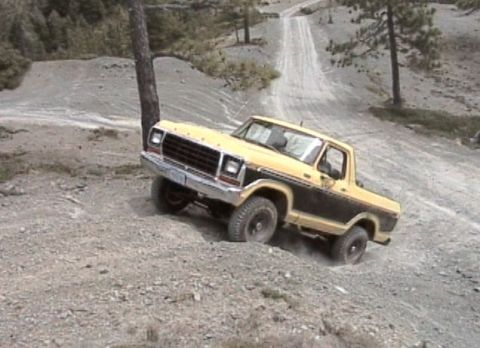 1979 Ford Bronco - Ford Bronco navigates a steep, rutted dirt track in a wooded, hilly area.