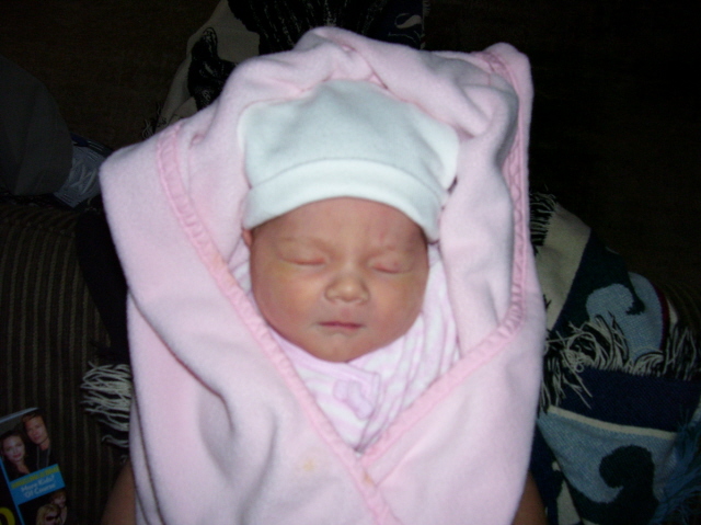 Baby wrapped in pink blanket and white hat, sleeping