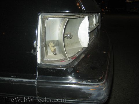 1985 Ford Mustang - The taillight housing on this black car is broken, revealing the bulb and internal components.