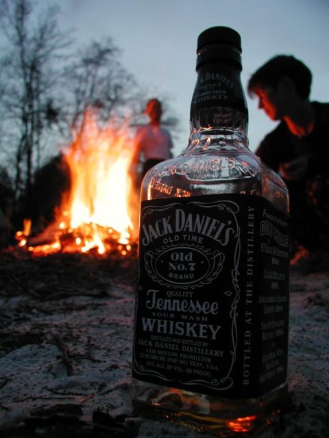 1989 Ford Bronco - A bottle of Jack Daniel's sits in the foreground with a campfire and two people in the background.