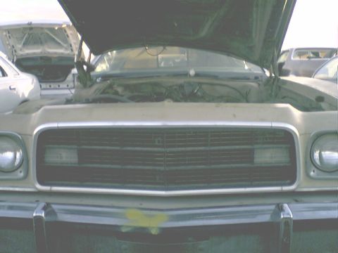 1973 Ford Ranchero - The front grille and headlights of a beige 1972 Ford Ranchero are visible with its hood open, alongside other vehicles.