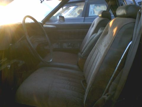 1973 Ford Ranchero - The interior of a car shows dusty tan seats and a steering wheel with sun glare.