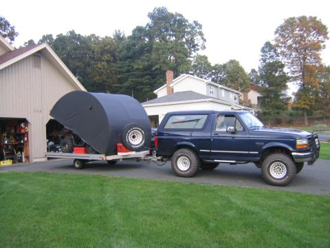 1994 Ford Bronco - A dark blue 1994 Ford Bronco is parked in a driveway, towing a trailer with a covered ATV.