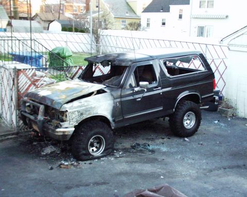 1989 Ford Bronco - This heavily damaged Ford Bronco shows extensive fire damage, including melted body panels and broken glass.