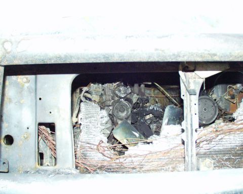 1989 Ford Bronco - Engine bay severely damaged by fire, showing melted parts and charred wiring.