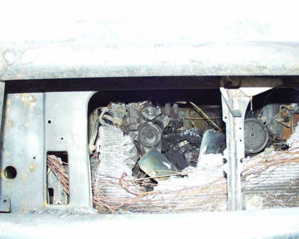 Burned engine bay with melted components and exposed wiring