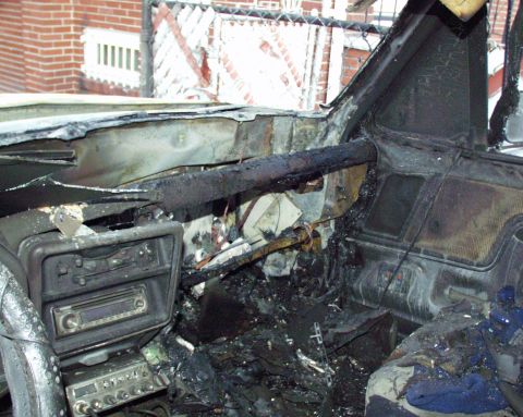 1989 Ford Bronco - Interior of a severely damaged vehicle after a fire, with extensive charring and debris visible.