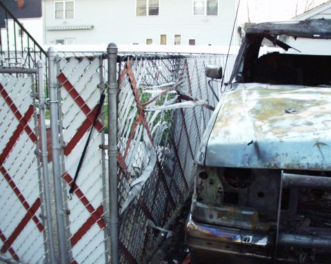 1989 Ford Bronco - A heavily damaged vehicle sits next to a broken chain-link fence.