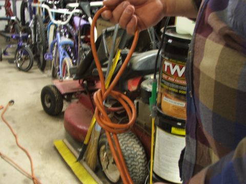 1965 Ford Mustang - A person holds a coiled orange extension cord in front of a red riding mower and several bicycles. A can of wood preservative is also visib…