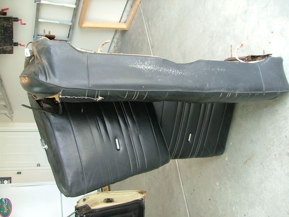 Black vinyl bench seat removed from vehicle, sitting on garage floor