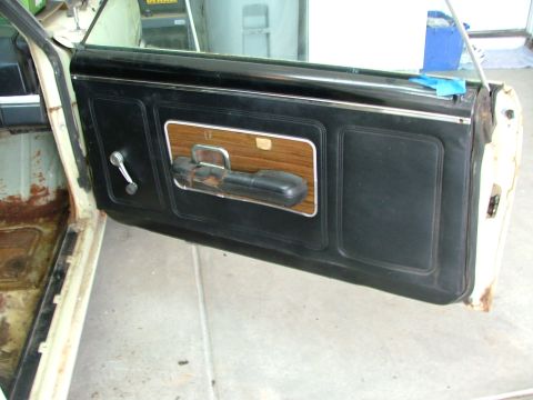 1969 Ford Ranchero - Close-up of a vehicle's interior door panel, black vinyl upholstery and faux woodgrain trim.